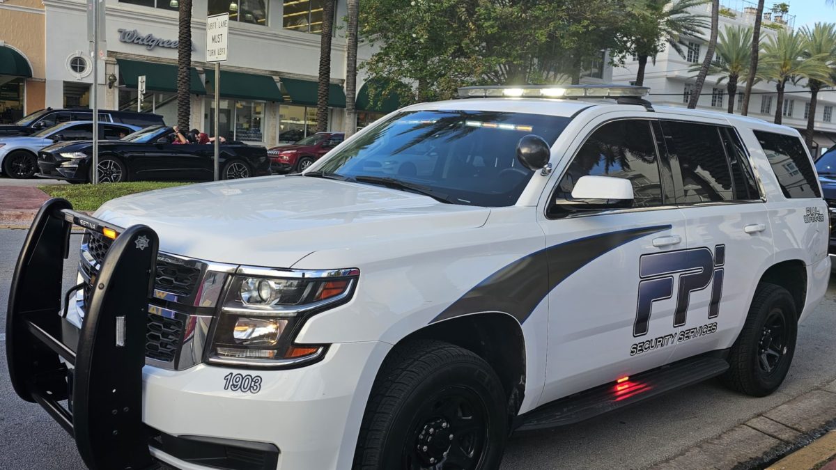 White FPI Security Services SUV parked outside on the street in Florida. It is a sunny day with some cars passing by.