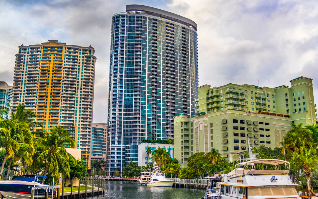 Picture of tall buildings located in Fort Lauderdale. Beneath the buildings is a body of water that has boats on it.