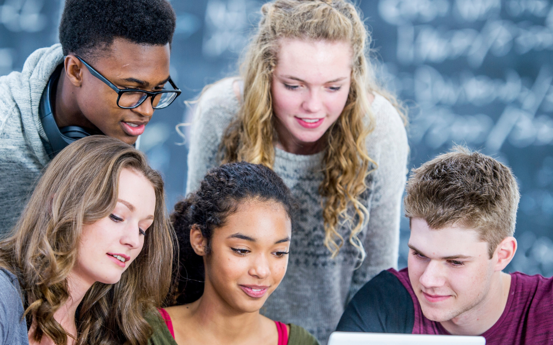 Here we have a picture showing Campus Safety for Students. There are 5 students sitting around a computer in the background you see a board with some white words on it.