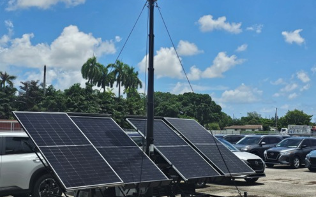 This is an image of the RIO360 security solution with solar panels and two cameras on top of a tall pole in the middle of a car lot. With a sunny day in the background and blue skies.