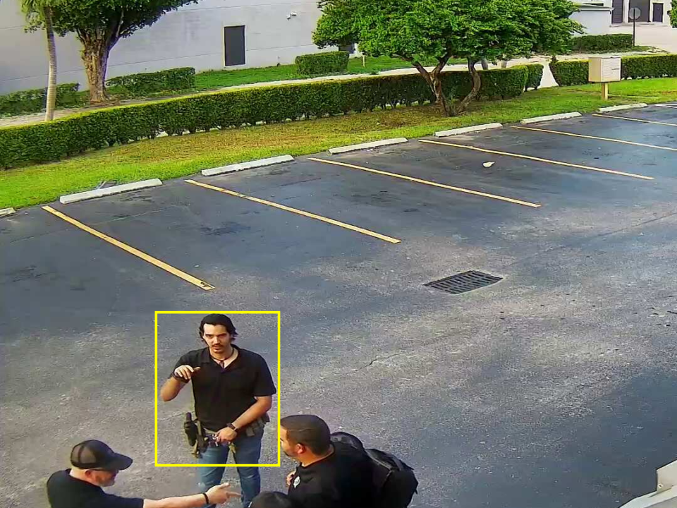 This is an image of 3 men wearing black shirts and jeans talking in the parking lot of Florida gun center located in Hialeah florida.