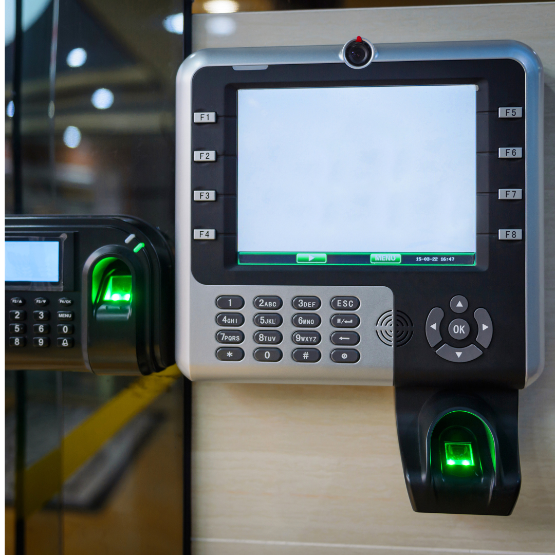 Photo of a keypad that is black and silver hanging on a wall with butttons for people to be let in. There is also a fingerprint scanner on the bottom of the keypad lit up in green. to the left of it is a mini keypad as wel. in black with a green fingerprint scanner also lit up.